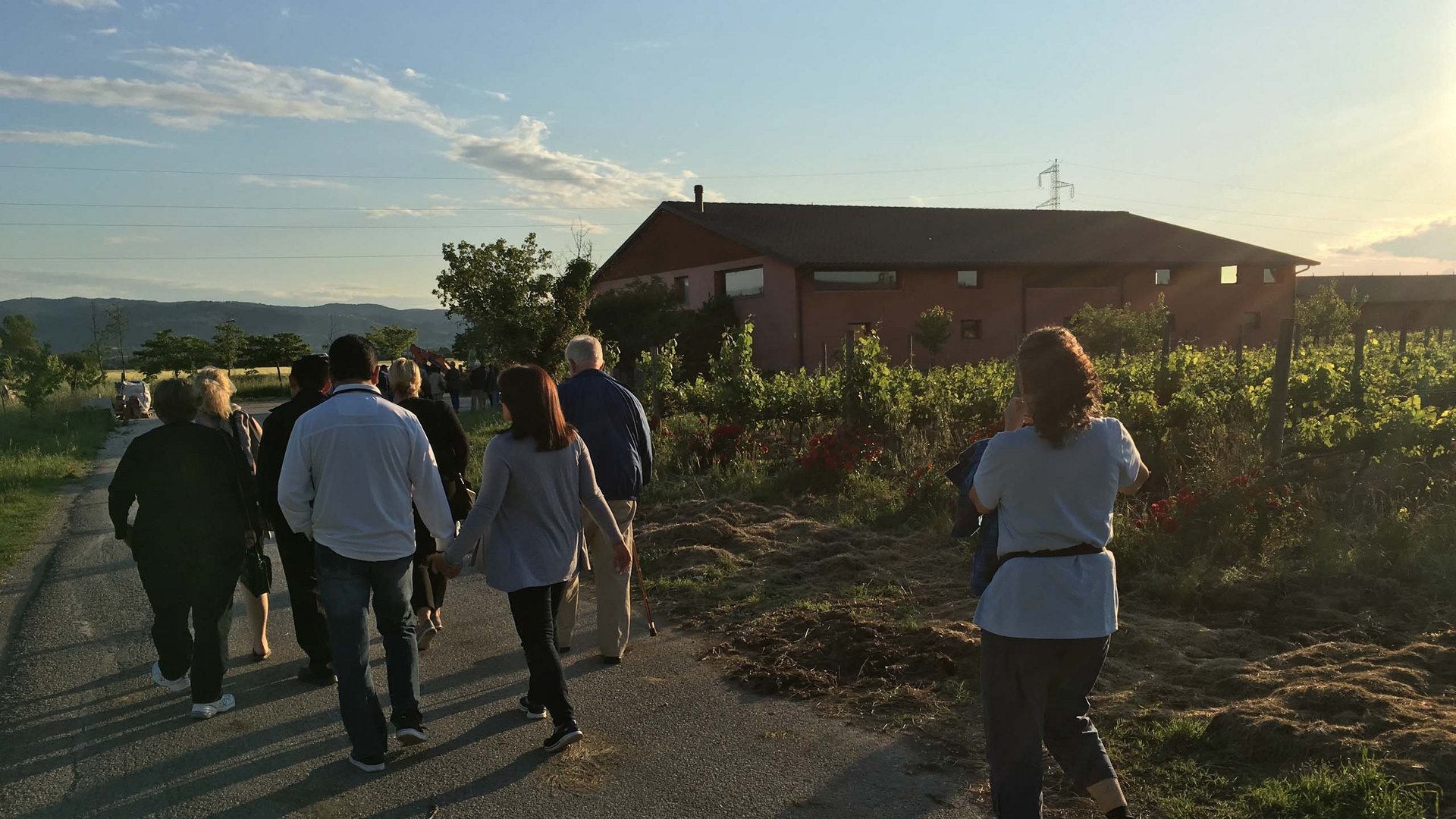 Ferienhaus in Umbrien mieten: für Teambuilding Gruppe von Menschen, die bei Sonnenuntergang auf einer Straße neben einem Bauernhaus gehen