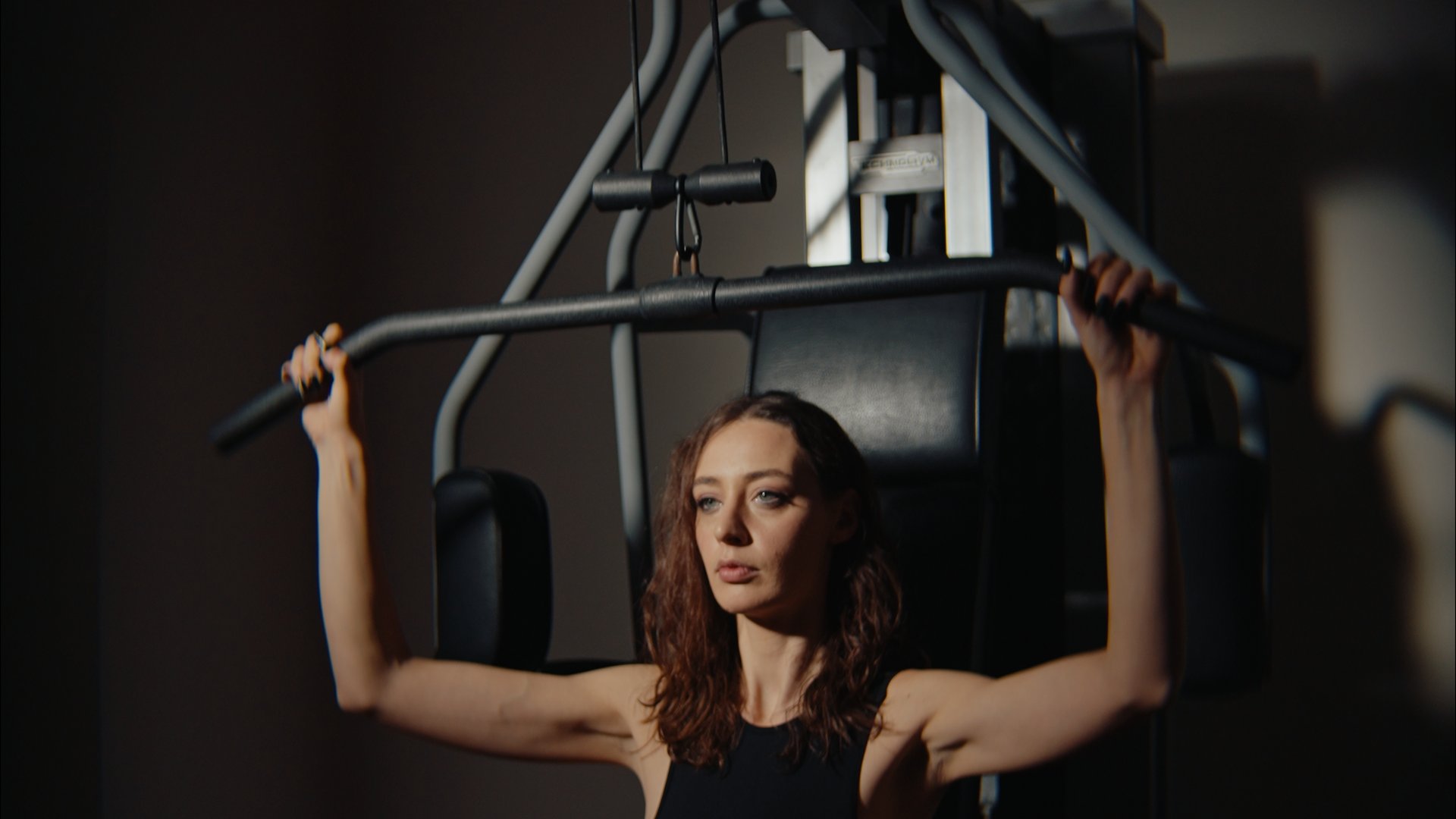 Frau trainiert an einem Latzuggerät im Fitnessstudio