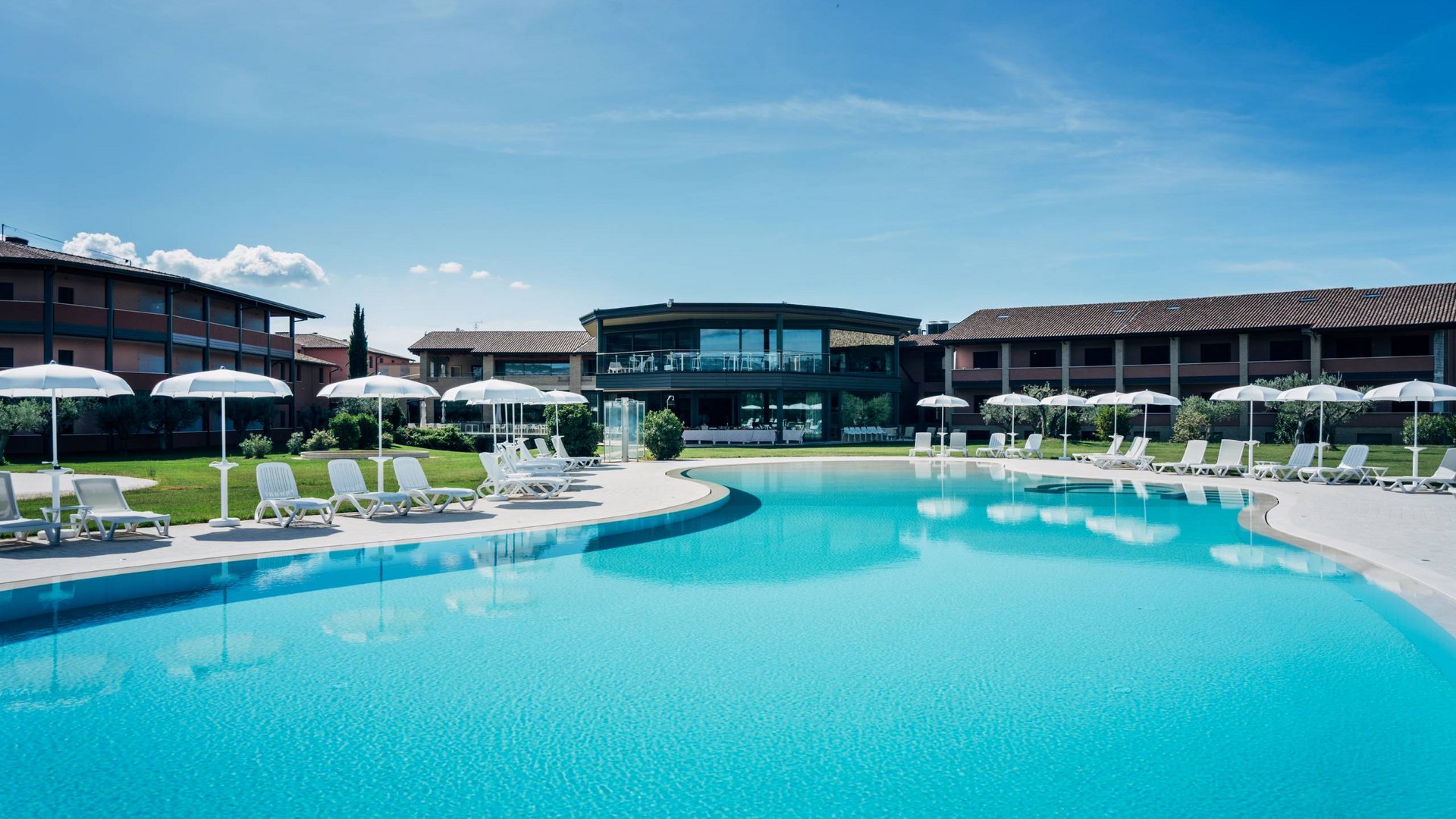 Urlaub in Umbrien? Und noch viel mehr! Außenpool mit Liegestühlen und Sonnenschirmen in einem modernen Resort