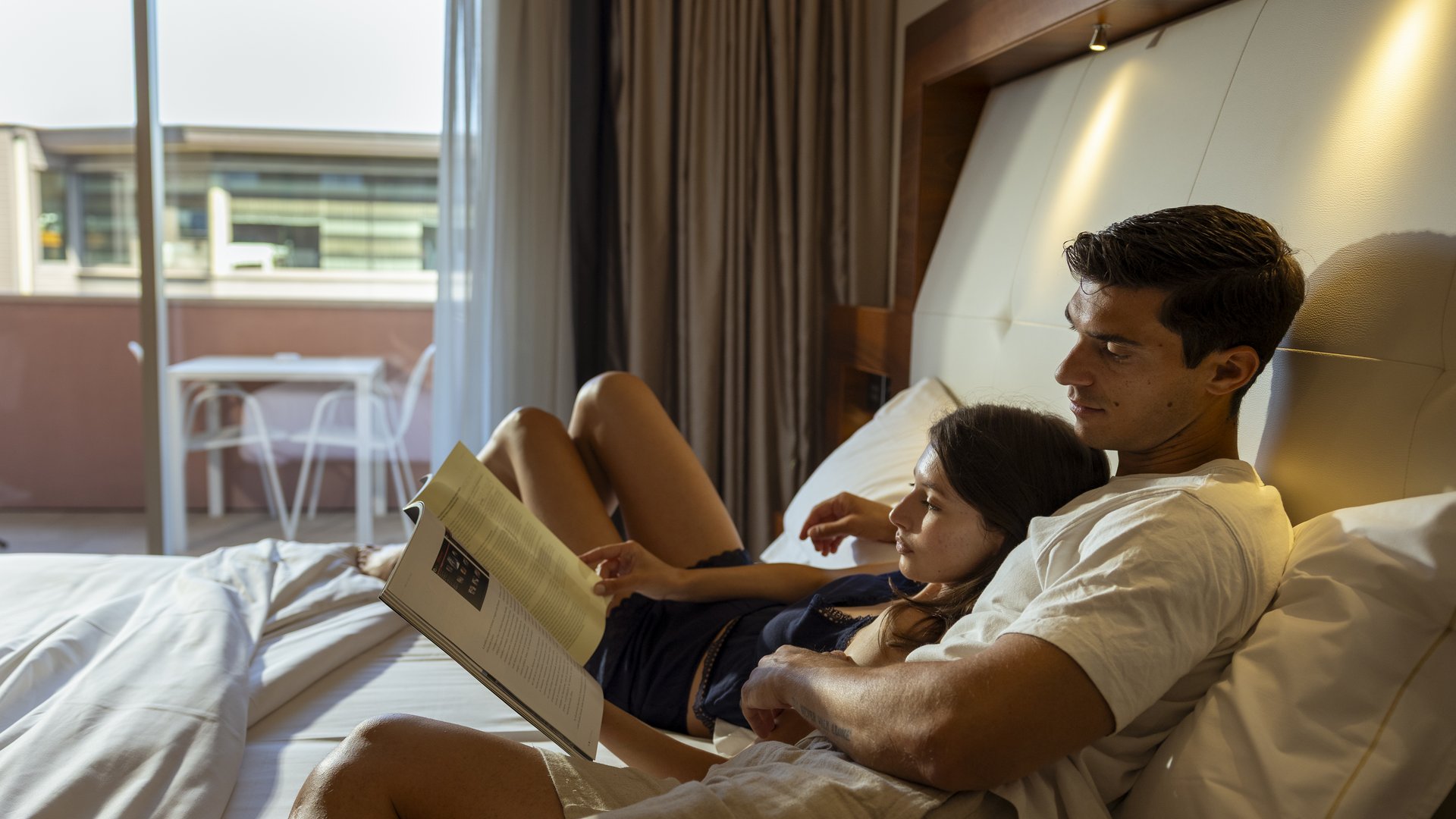 Das Hotel bei Assisi, das Sie gesucht haben Paar liest zusammen im Hotelzimmer auf dem Bett mit Balkon