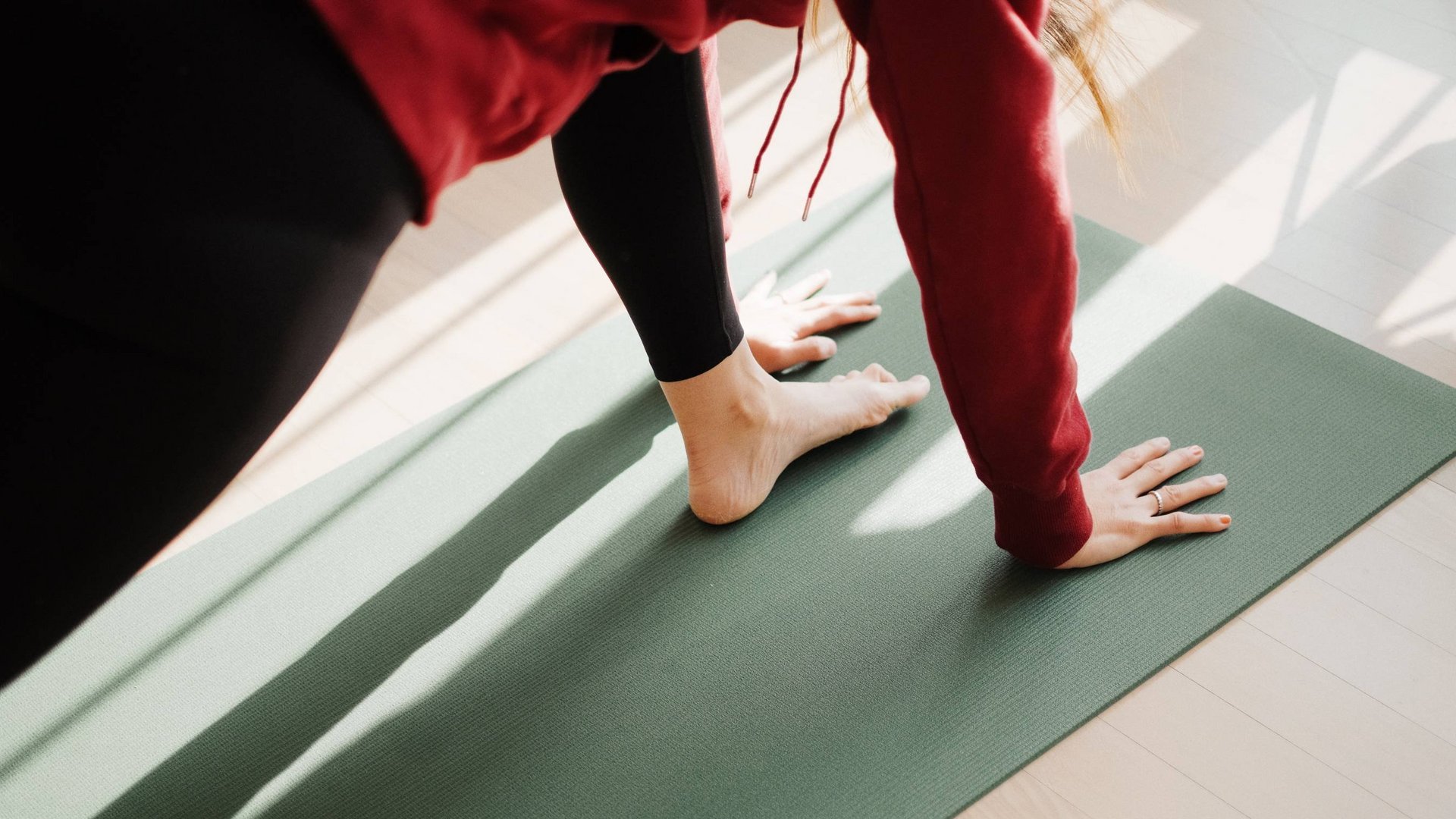 Un hotel con spa per famiglie e area fitness Persona che fa yoga su un tappetino verde in una stanza luminosa